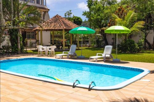 una piscina con sillas y sombrillas en un patio en Pousada Mar do Santinho, en Florianópolis