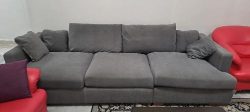 a grey couch in a living room with two red chairs at The CRISNA'S Apartment in Port Dickson
