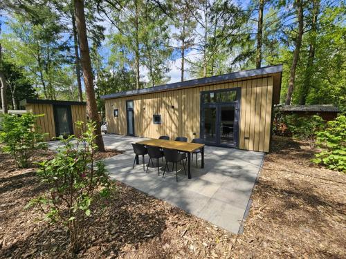 a small cabin with a table and chairs on a patio at Boshuis de Boompjes in Doornspijk