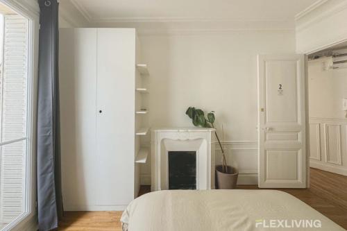 une chambre blanche avec un lit et une cheminée dans l'établissement Flexliving - Room - Lamarck, à Paris