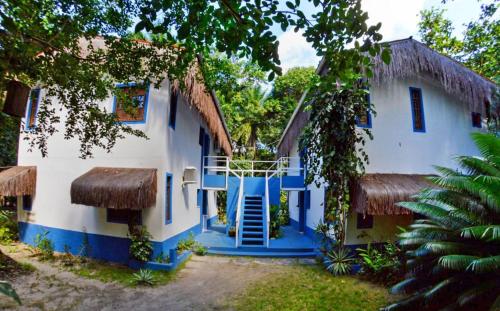 a house with a blue and white facade and trees at POUSADA e BANGALOS VILA DA BARCA in Ilha de Boipeba