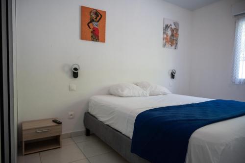 a bedroom with a bed with a blue blanket at Résidence ATLAS in Saint-Laurent du Maroni