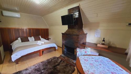 ein Schlafzimmer mit einem Bett, einem Kamin und einem TV in der Unterkunft Villa Chalés Gramado - OH HOTÉIS in Gramado