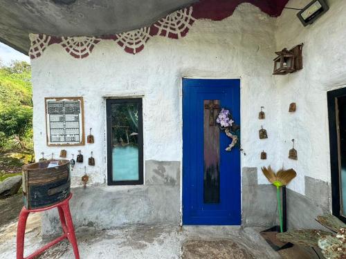 a house with a blue door and a chair at Clay House Chiang Mai By Alphatel in Chiang Mai