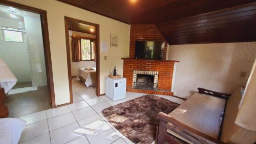 uma sala de estar com lareira e televisão em Villa Chalés Gramado - OH HOTÉIS em Gramado