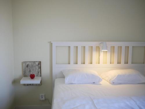uma cama com lençóis e almofadas brancos e um candeeiro em Jädra Gårdshotel em Enköping