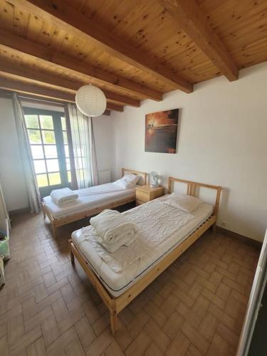 une chambre avec deux lits et une grande fenêtre dans l'établissement Maison de Vacances Rayons de soleil, à Notre-Dame-de-Monts