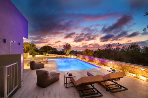 a swimming pool on a patio with a sunset at LILY'S VILLA LEMONIA in Platanes