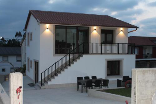 a house with a balcony with a table and chairs at Apartamentos Camino Inglés II in Ordes