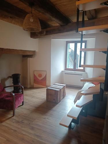 un salon avec un escalier, une chaise et une fenêtre dans l'établissement L'échappée belle de l'Aubrac, à Saint-Chély-dʼAubrac