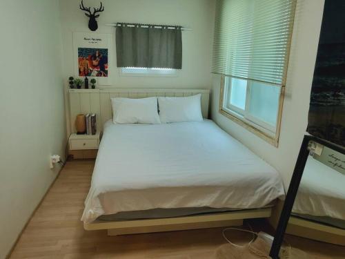 a bedroom with a bed with white sheets and a window at Seeun house in Gwangju