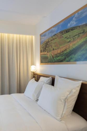 a bed with white pillows in a hotel room at Hôtel Restaurant La Vallée Noble, proche Eguisheim Colmar in Soultzmatt