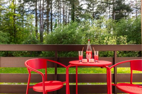 a red table with two chairs and a bottle on it at Hôtel Restaurant La Vallée Noble, proche Eguisheim Colmar in Soultzmatt