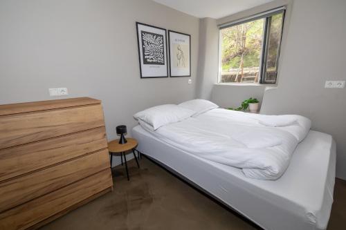 Schlafzimmer mit einem Bett mit weißer Bettwäsche und einem Fenster in der Unterkunft Apartment close to downtown in Akureyri