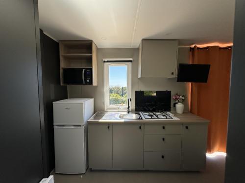 une petite cuisine avec un évier et une cuisinière dans l'établissement Le Laurier, mobil-home climatisé avec vue sur mer, à Hyères