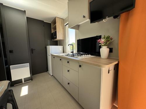 une cuisine avec des armoires blanches et un four à plaques de cuisson dans l'établissement Le Laurier, mobil-home climatisé avec vue sur mer, à Hyères