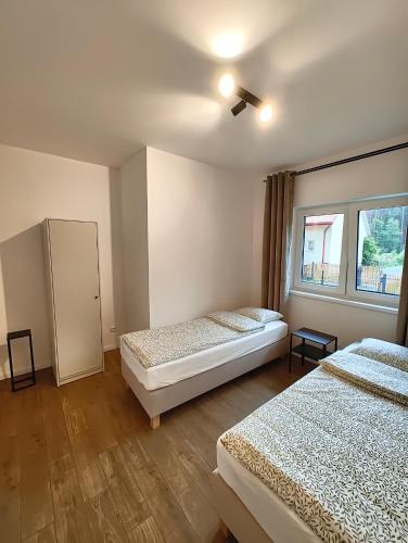 a bedroom with two beds and a window at Apartament Szum in Susiec