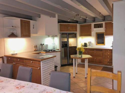 une cuisine avec des armoires en bois et une table avec des chaises dans l'établissement Les Gouttes Hôtes - Maison de charme, à Essertines-en-Châtelneuf