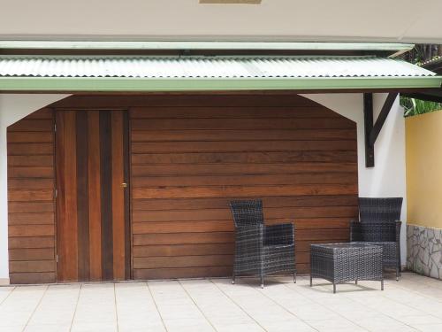 a wooden garage with two chairs under awning at Kaz' Évasion plage & jacuzzi - REMIRE-MONTJOLY in Montjoly