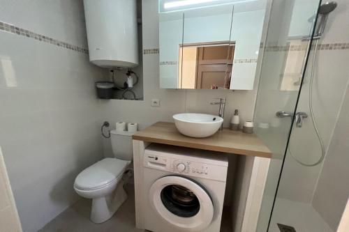 une salle de bain avec une machine à laver et un lavabo dans l'établissement sympathique T2 dans un super village vacance Hawaï 5, à Canet