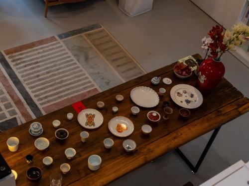 a wooden table with cups and plates and a vase at 景德镇树园心舍民宿JDZ Forest Haven B&B in Jingdezhen