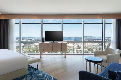 a living room with a tv and large windows at Wyndham Grand Istanbul Levent Hotel & Conference Center in Istanbul
