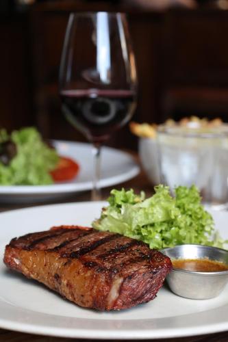 a plate of food with a piece of steak and a glass of wine at The Porterhouse grill & rooms in Oxford