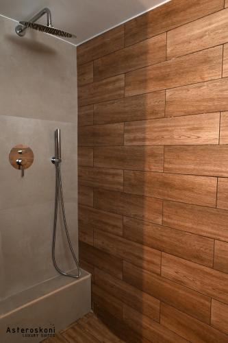 a bathroom with a shower with a wooden wall at Asteroskoni Luxury Suites in Nafplio