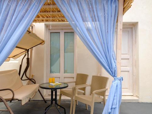 Habitación con sillas, mesa y cortinas azules en Nalu Suites, en Fira