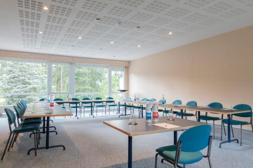 a conference room with tables and chairs and windows at Hôtel Restaurant La Vallée Noble, proche Eguisheim Colmar in Soultzmatt