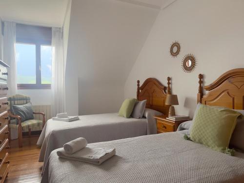 a bedroom with two beds and a chair and a window at Casona de la Loma - 2806 in San Mamés de Meruelo