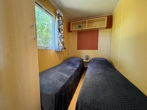 deux lits dans une petite pièce avec une fenêtre dans l'établissement Le Romarin, mobil-home climatisé avec vue sur la mer, à Hyères