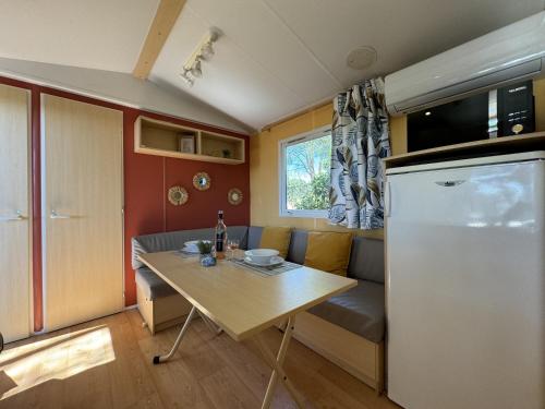 une cuisine et une salle à manger avec une table et un réfrigérateur dans l'établissement Le Romarin, mobil-home climatisé avec vue sur la mer, à Hyères