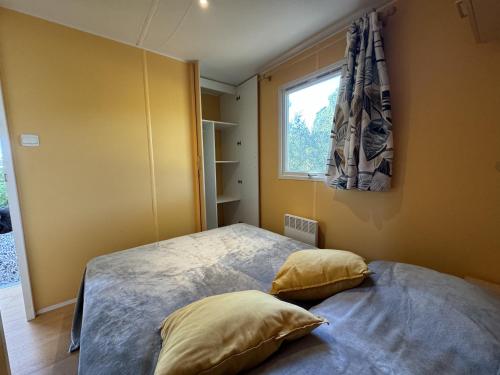 - une chambre avec un lit avec deux oreillers et une fenêtre dans l'établissement Le Romarin, mobil-home climatisé avec vue sur la mer, à Hyères