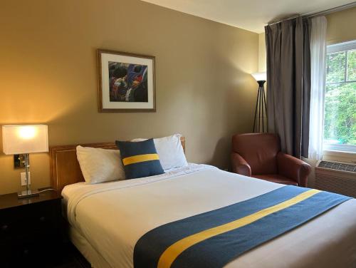 a hotel room with a bed and a chair at Hôtel Énergie Shawinigan in Shawinigan