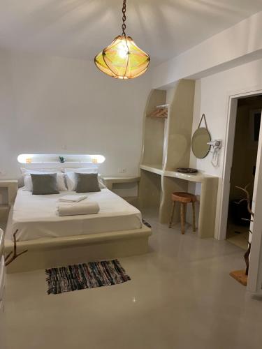 a white bedroom with a bed and a chandelier at Alexandra’s studios in Iraklia