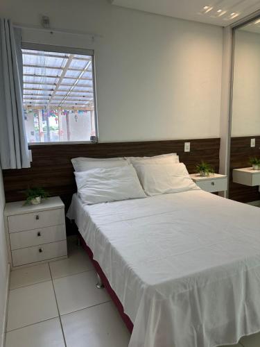 a bedroom with a large white bed with a window at Apartamento Cond Leão Dourado 01 in Caruaru