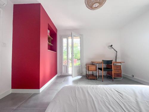 Cette chambre comprend un bureau et un mur rouge. dans l'établissement villa avec piscine et grand jardin, à Nîmes