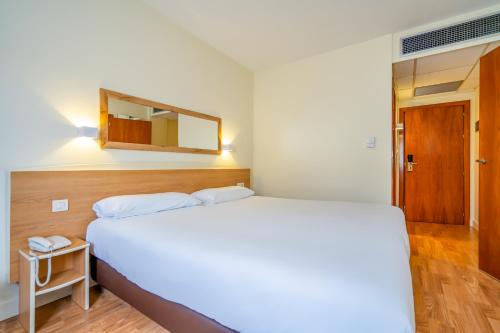 1 dormitorio con cama blanca y espejo en Hotel YIT Ciudad de Elche, en Elche