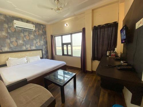 a bedroom with a bed and a table and a couch at Hotel Sita Place On Heritage Ghats Of Benaras in Varanasi