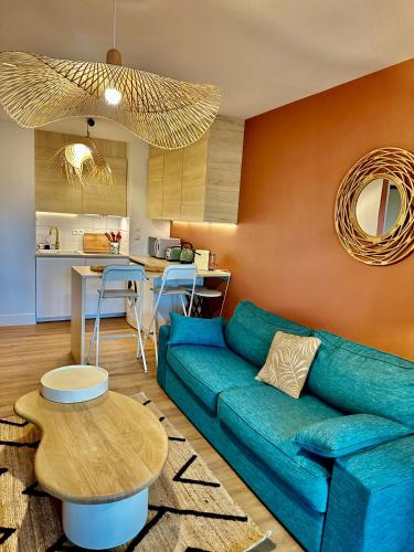 un salon avec un canapé bleu et une table dans l'établissement Le Quai Secret d'Augustine, à Narbonne