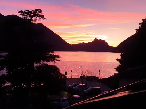 a sunset over a body of water with a mountain at Modern apartament in Porlezza