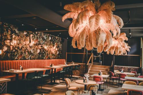 a restaurant with tables and chairs and a chandelier at Hotel Centraal Baarlo in Baarlo