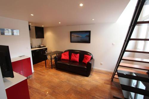 un salon avec un fauteuil en cuir avec des coussins rouges dans l'établissement Confortable Studio Carré d'OR 2Pers, rez-de-chaussée, à Marseille