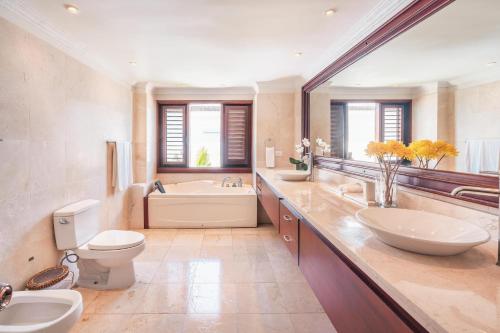 a bathroom with two sinks and a tub and a toilet at Seaside Bliss with pool and spectacular view in Las Minas