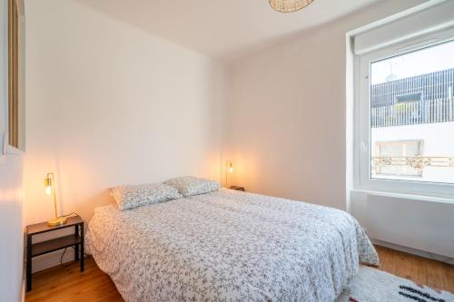 une chambre blanche avec un lit et une fenêtre dans l'établissement T2 cosy à deux pas de la gare, à Nantes