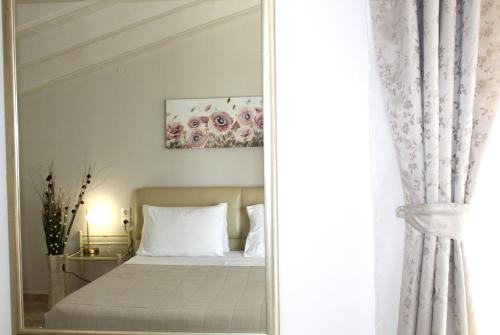 a mirror in a bedroom with a bed and a painting at Fissas Rooms in Sivota