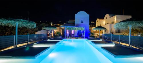 a swimming pool with blue lights in front of a building at Nalu Suites in Fira