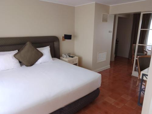 a bedroom with a white bed and a table and chair at Suites del Bosque Hotel in Lima