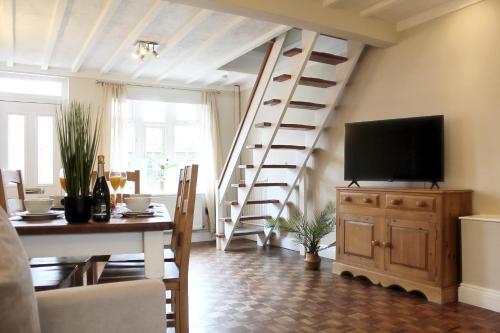 a living room with a staircase with a television and a table at Cosy Cottage in Mersea - Walking distance to beach and town in West Mersea